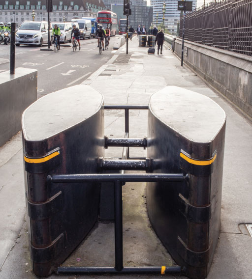 A terrorist drove a car into pedestrians along the Westminster Bridge in London in 2017. Fifty people were injured, four were killed. He then crashed the car into the perimeter fence of the palace grounds and ran into New Palace Yard, where he fatally stabbed an unarmed police officer. He was then shot by an armed police officer and died. The barriers shown in the image were installed to prevent such an attach from happening again.