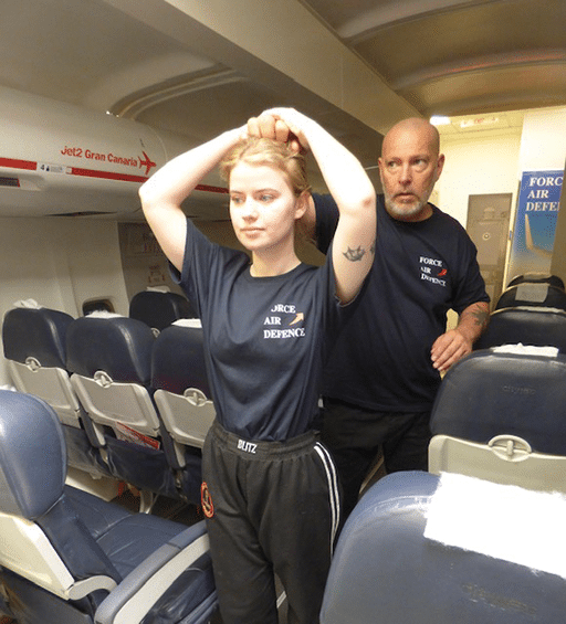 All self-defense maneuvers are practiced both in the classroom and in a simulated aircraft cabin to duplicate the look and feel of where these events actually occur. Shown left, is how to work together to restrain a passenger on board. Shown right are participants demonstrating the hair pull response in the aircraft as seen in the classroom on page 24.